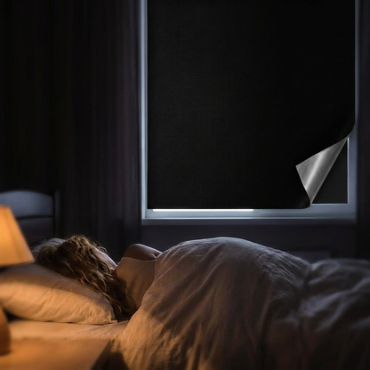 Adhesive blackout window shade installed in dark cozy bedroom