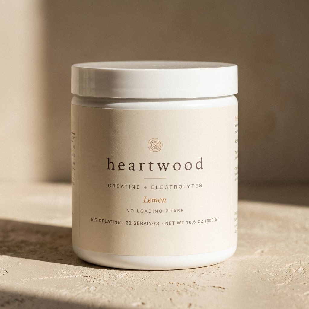 Heartwood Creatine + Electrolytes tub on a warm plaster surface in hard morning light
